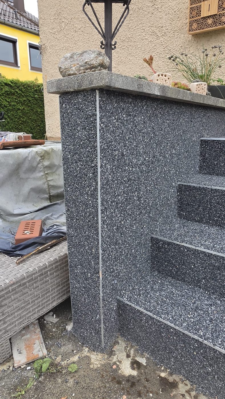Seitenwand einer Treppe mit Steinteppich und Edelstahlprofil an der Kante