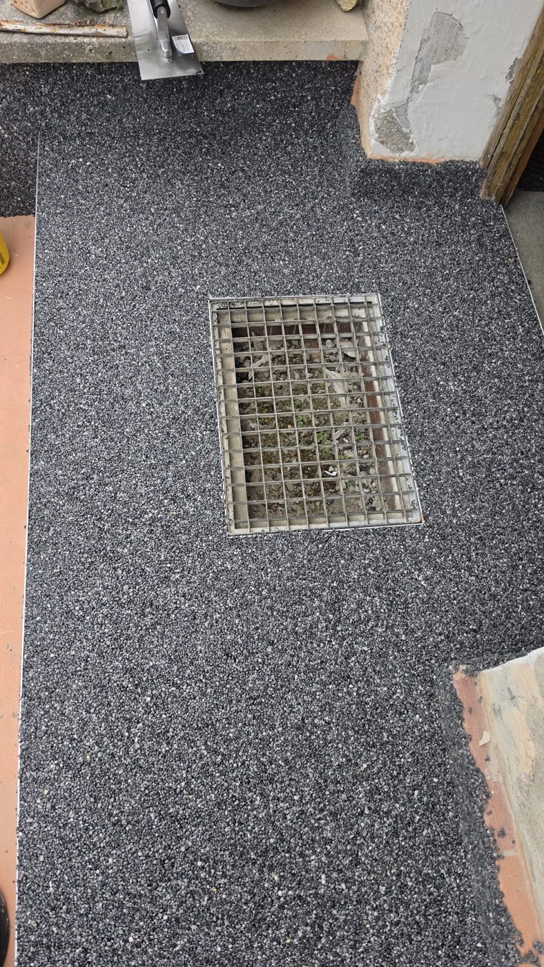 Podest vor der Haustür mit Steinteppich, eingefasst um einen Gitterrost